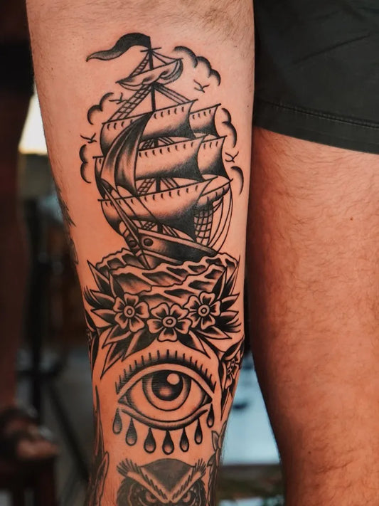 Big Traditional Ship Flowers Eye Tattoo on Men Leg by @figtree.tattoo.studio