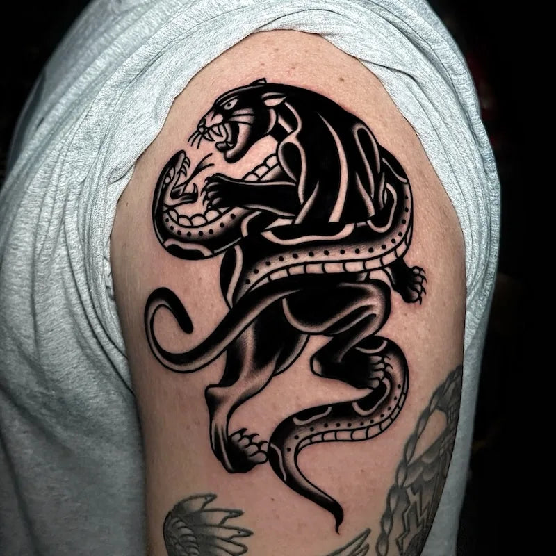 black panther and snake fighting traditional tattoo on man upper arm