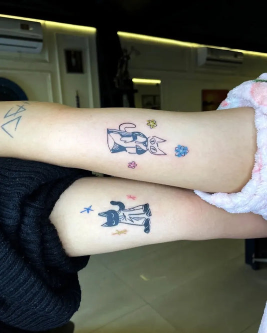 Matching Neotraditional Cat Characters Tattoo on Women Bicep by @artufie