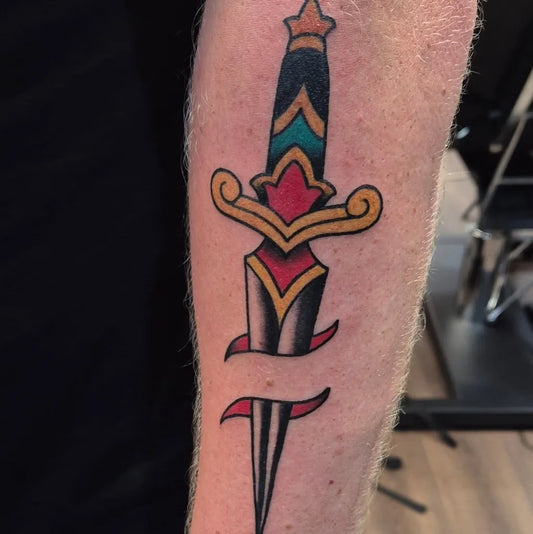 Medium American Traditional Dagger with Banner Tattoo on Men Arm by @byrne_tattoos