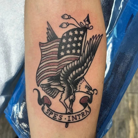 Medium American Traditional Eagle with Flag and Banner Military Tattoo on Men Arm by @americantattoosociety