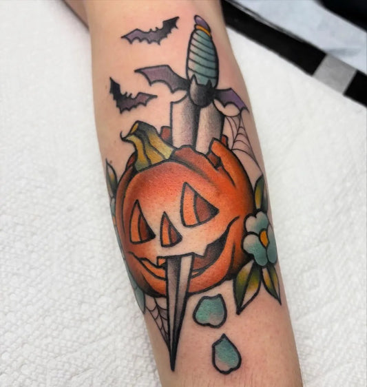 Medium American Traditional Pumpkin Dagger Bats Halloween Tattoo on Women Arm by @bailey.parke