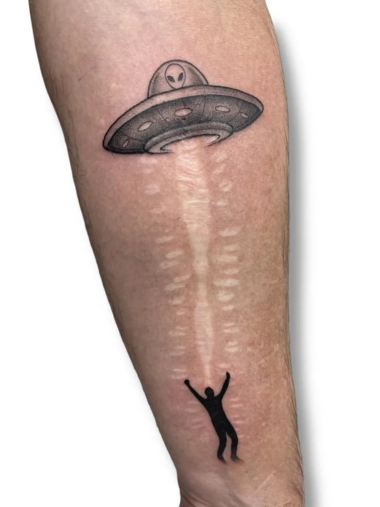 Medium Black and Grey Alien UFO Abduction Coverup Tattoo on Men Arm by @inkwave.tattoo.fuerteventura
