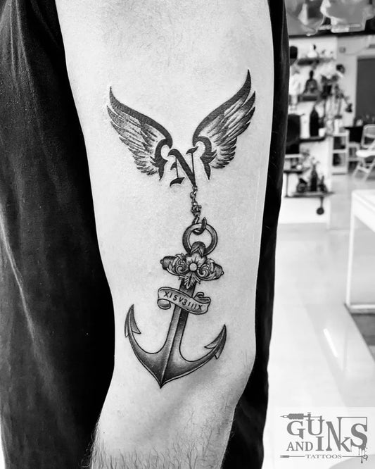 Medium Black and Grey Anchor with Wings and Chain Tattoo on Men Arm by @gunsandinkstattoos