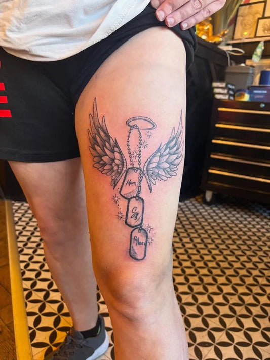 Medium Black and Grey Angel Wings Dog Tags Tattoo on Men Thigh by @tattoosbytx