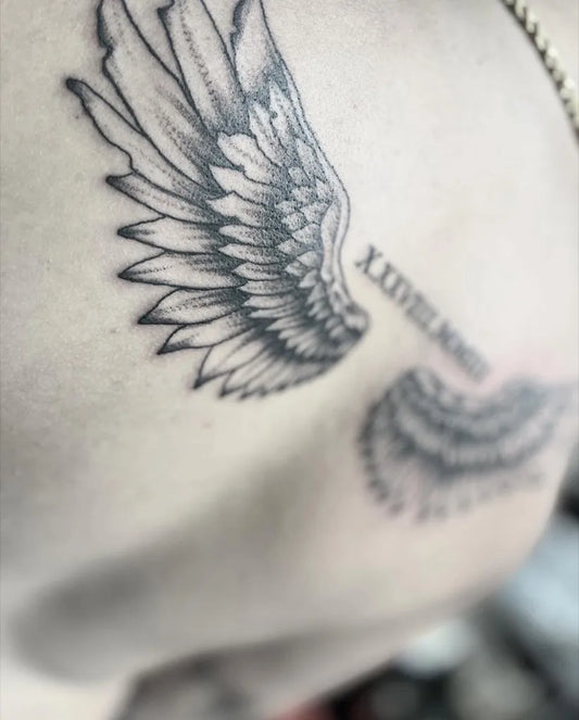 Medium Black and Grey Angel Wings Roman Numerals Tattoo on Men Shoulder by @artbyannistyn