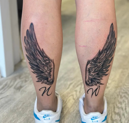 Medium Black and Grey Angel Wings with Letters Tattoo on Women Legs by @inez_tattoo_ink