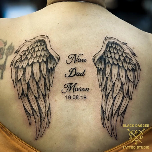 Medium Black and Grey Angel Wings with Names Tattoo on Women Back by @blackdaggertattoonorwich