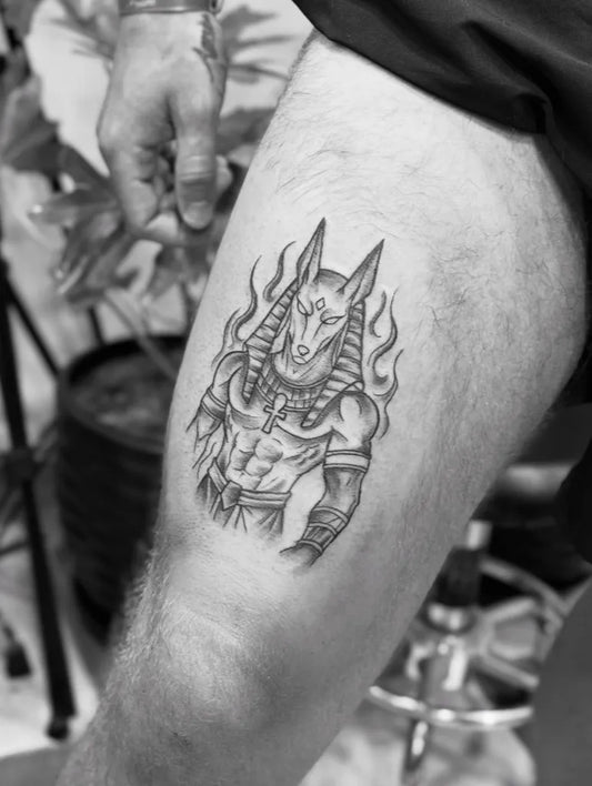 Medium Black and Grey Anubis with Flames and Muscular Figure Tattoo on Men Thigh by @dr_g_tattoo_hurghada