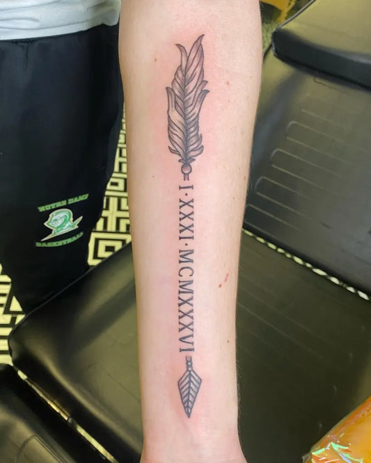 Medium Black and Grey Arrow with Feather and Roman Numerals Tattoo on Men Arm by @yellowhearts.ink