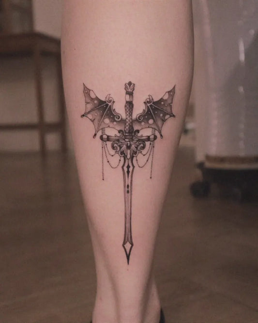 Medium Black and Grey Bat Winged Sword Tattoo on Women Leg by @zaal.tt