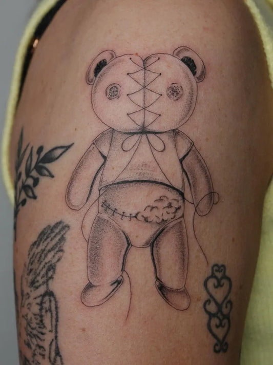Medium Black and Grey Bear with Stitches and Heart on Women Arm Tattoo by @carlyjordyn