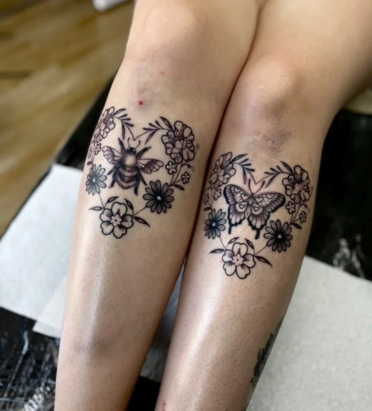 Medium Black and Grey Bee Butterfly Flowers on Women Legs Tattoo by @foxx.teeth_