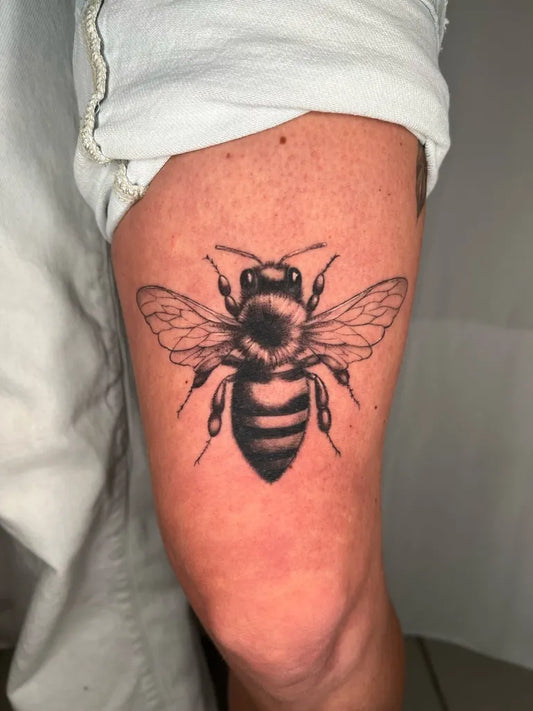 Medium Black and Grey Bee on Women Thigh Tattoo by @nikelangelo_tattoo