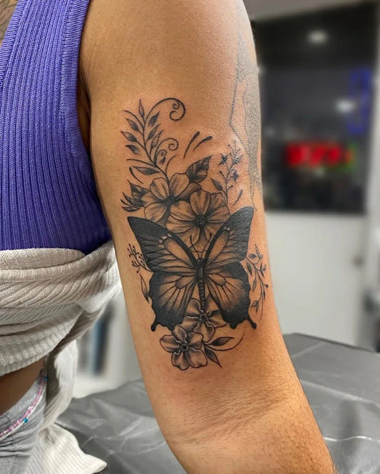 Medium Black and Grey Butterfly and Flowers Tattoo on Women Bicep by @malobita