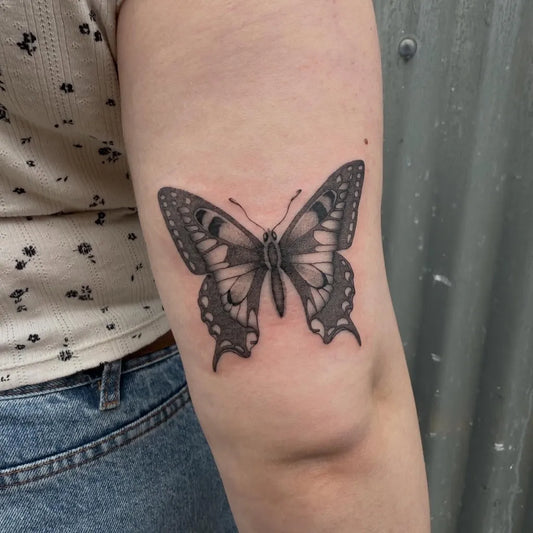 Black and Grey Butterfly on Women Upper Arm Tattoo by @macarthur.tattoos