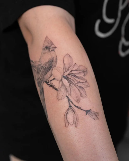 Medium Black and Grey Cardinal and Magnolia Tattoo on Women Arm by @lilyblu.ink