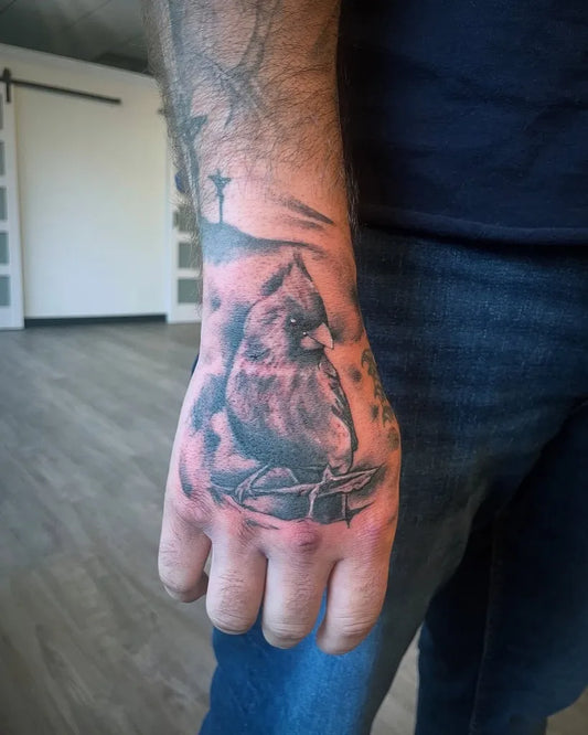 Medium Black and Grey Cardinal with Cross and Landscape Tattoo on Men Hand by @craneco_tattoo