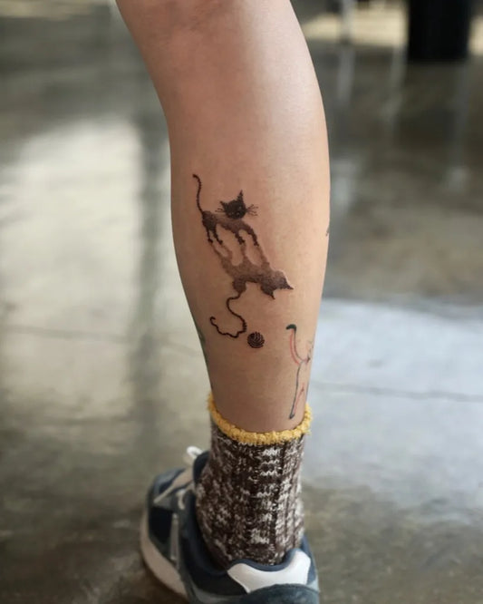 Medium Black and Grey Cat and Yarn Ball Nature Tattoo on Women Leg by @jangmi.ink