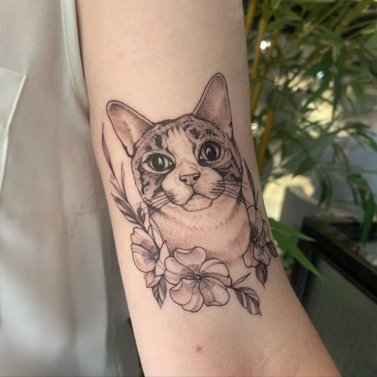 Medium Black and Grey Cat with Flowers Tattoo on Women Arm by @cornelia.tattoos