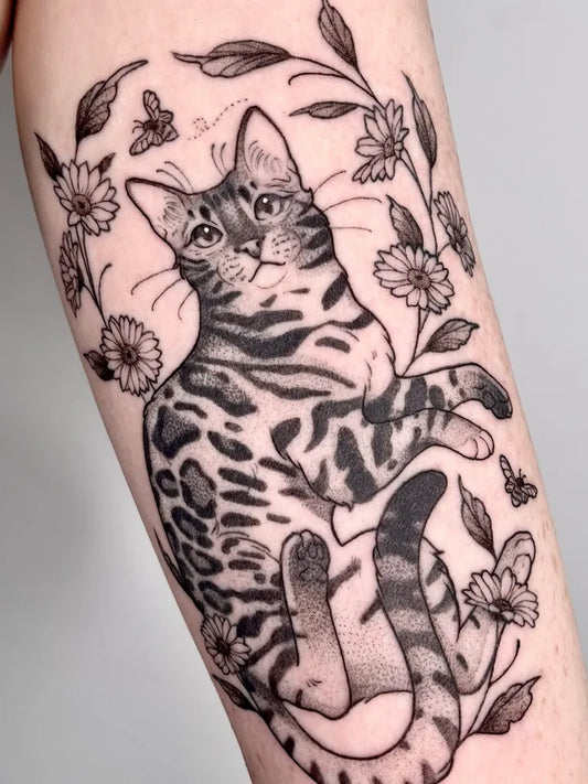 Medium Black and Grey Cat with Flowers and Bees Tattoo on Women Arm by @helle.ink