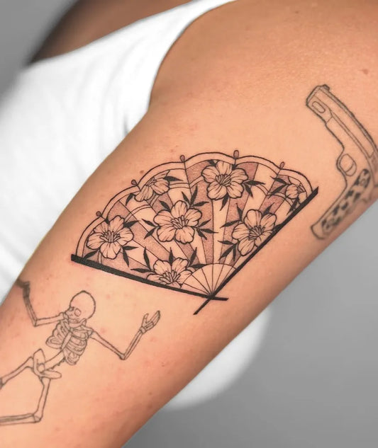 Medium Black and Grey Cherry Blossom Fan and Skeleton with Gun on Women Arm Tattoo by @tayco.tattoo