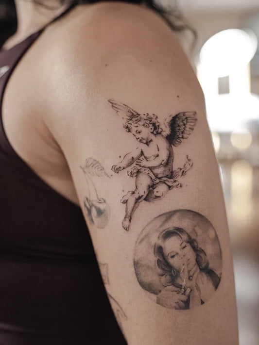 Medium Black and Grey Cherub and Winged Portrait Tattoo on Women Shoulder by @ab.ink__
