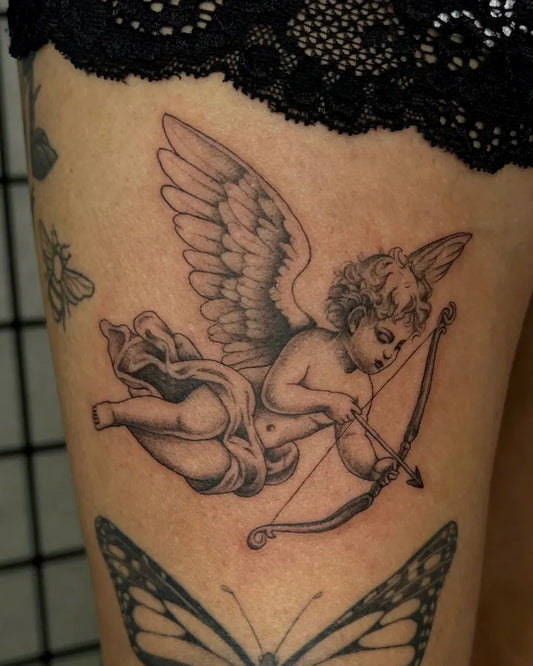 Medium Black and Grey Cherub with Bow and Arrow Tattoo on Women Thigh by @atrinalizztattoo