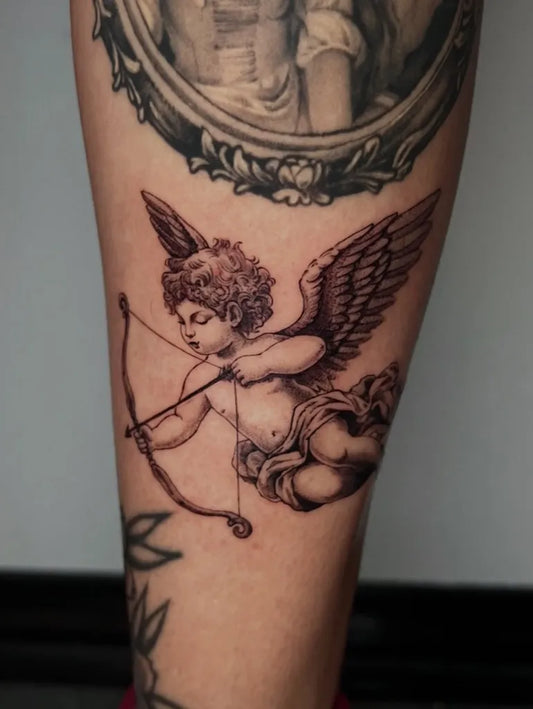 Medium Black and Grey Cherub with Bow and Frame Tattoo on Women Arm by @bloodkimchi