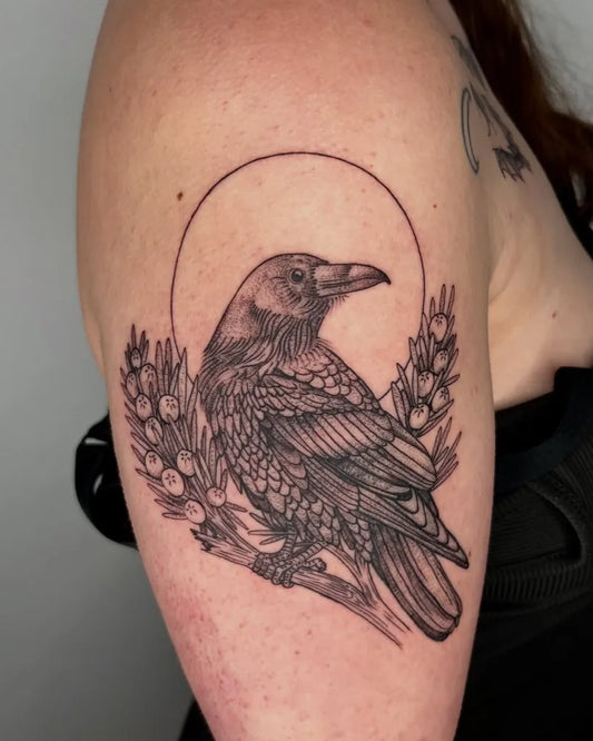 Medium Black and Grey Crow with Halo and Berries Tattoo on Women Upper Arm by @iriswoodtattoo