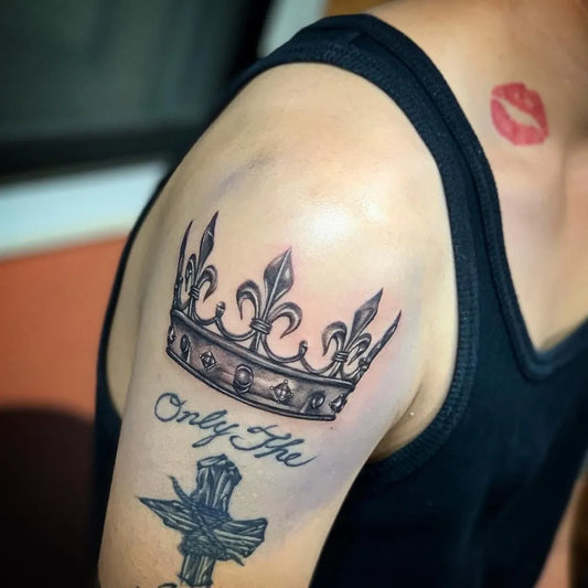 Medium Black and Grey Crown and Fleur de lis Tattoo on Men Upper Arm by @strokertattoo