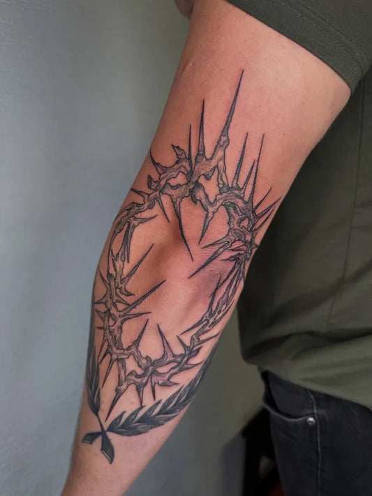 Medium Black and Grey Crown of Thorns with Laurel Tattoo on Men Elbow by @sykorkatattoo