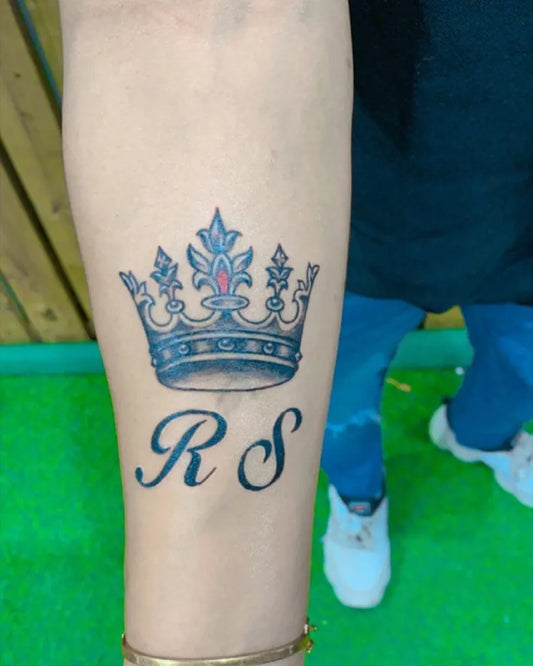 Medium Black and Grey Crown with RS Letters Tattoo on Women Arm by @theamit_tattooz