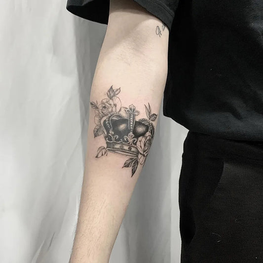Medium Black and Grey Crown with Rose and Leaves Tattoo on Men Arm by @lulu.ttttttt
