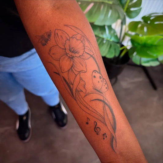 Medium Black and Grey Daffodil Butterfly and Musical Notes Tattoo on Women Arm by @aka.jas