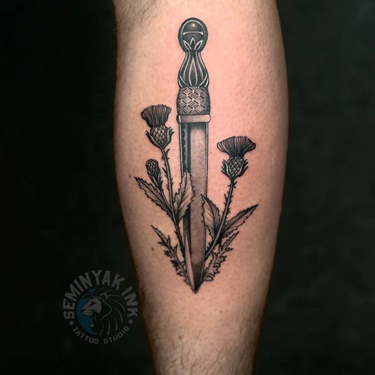 Medium Black and Grey Dagger and Thistles Tattoo on Men Leg by @seminyakinkbali