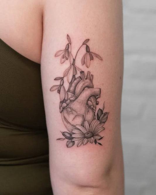 Medium Black and Grey Daisy Anatomical Heart Tattoo on Women Arm by @lilyblu.ink