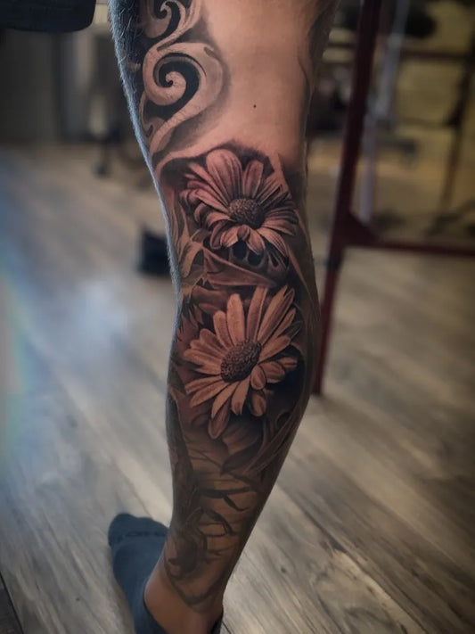 Medium Black and Grey Daisy Flowers Tattoo on Men Leg by @aaronthomastattoos