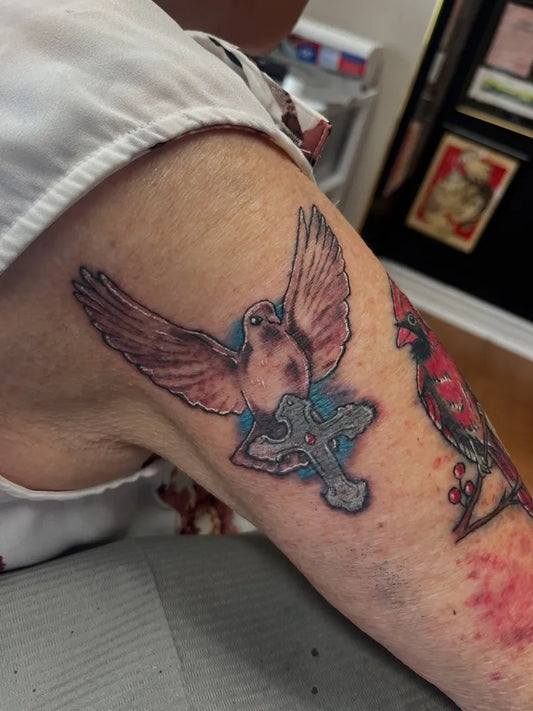 Medium Black and Grey Dove with Cross Tattoo on Women Arm by @nate.hartley.tattoos