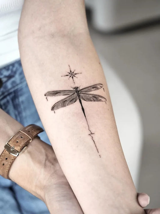 Medium Black and Grey Dragonfly with North Star on Women Arm Tattoo by @dominikzky.tattoo