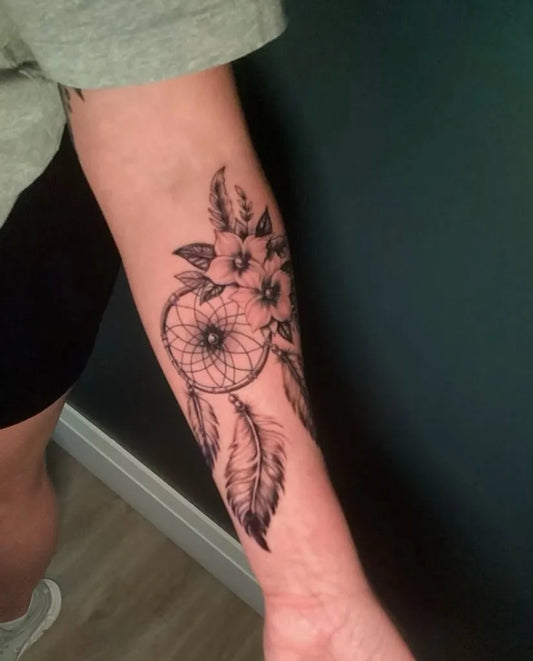 Medium Black and Grey Dream Catcher with Flowers and Feathers Tattoo on Men Arm by @bondtattooinc