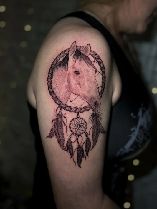 Medium Black and Grey Dream Catcher with Horse Tattoo on Women Upper Arm by @tama_diamonddog