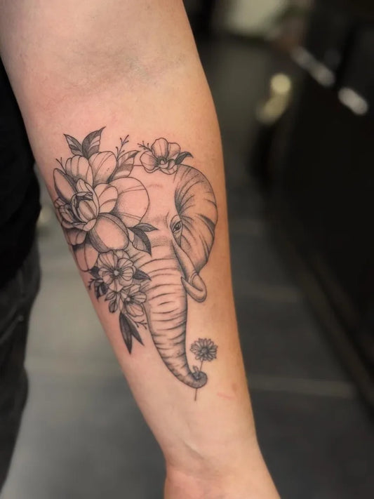 Medium Black and Grey Elephant and Flowers Tattoo on Women Arm by @somi.ink