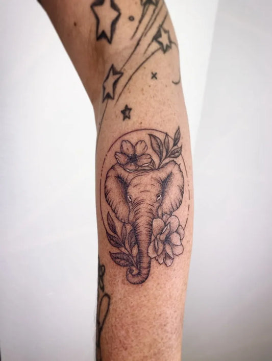 Medium Black and Grey Elephant with Flowers Tattoo on Women Arm by @odyssey.tattoo