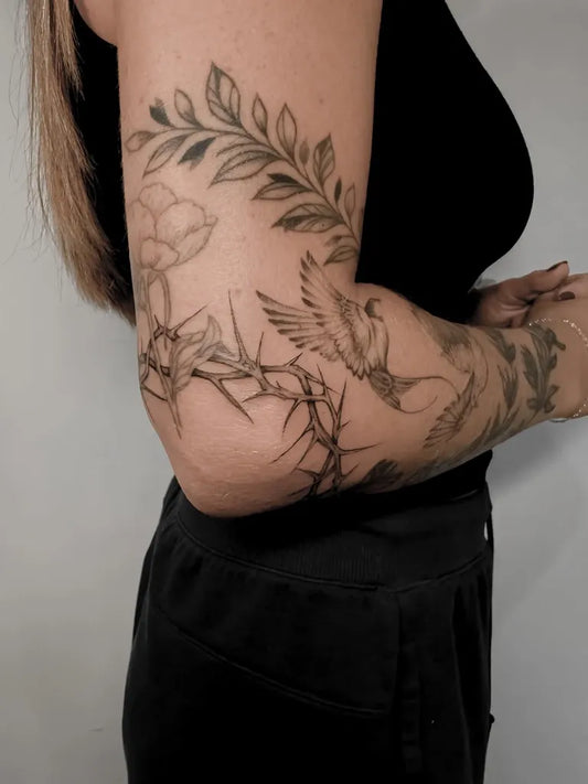 Medium Black and Grey Floral Bird Tattoo on Women Elbow by @lexieroseart