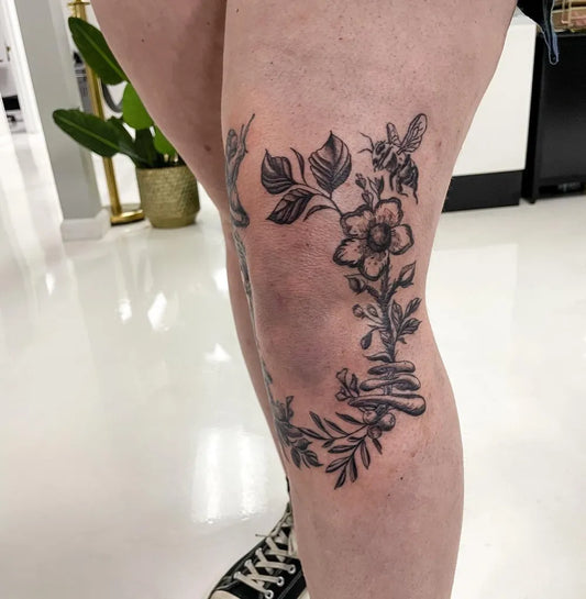 Medium Black and Grey Flower and Bee Tattoo on Women Knee by @sandman.ttt