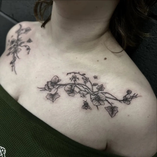 Medium Black and Grey Flowers Vines and Bee Tattoo on Women Collarbone by @mayraetats