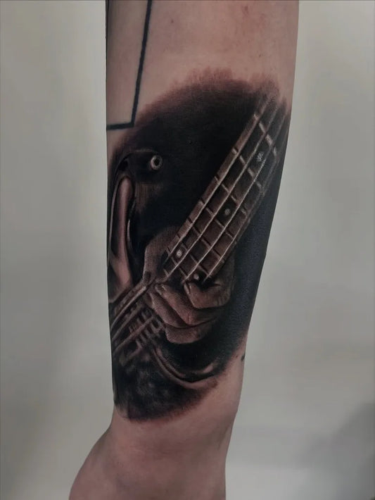 Medium Black and Grey Hand Playing Bass Guitar Music Tattoo on Men Arm by @beckyfostertattoo