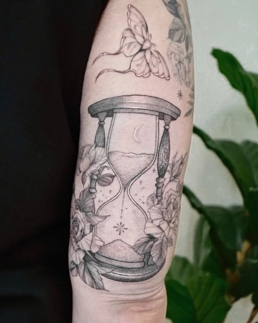 Medium Black and Grey Hourglass with Flowers and Butterfly Tattoo on Women Arm by @carbonreverie