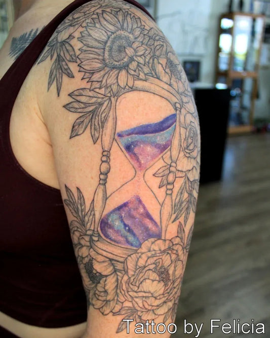 Medium Black and Grey Hourglass with Flowers and Leaves Tattoo on Women Arm by @tigerlotustattoo